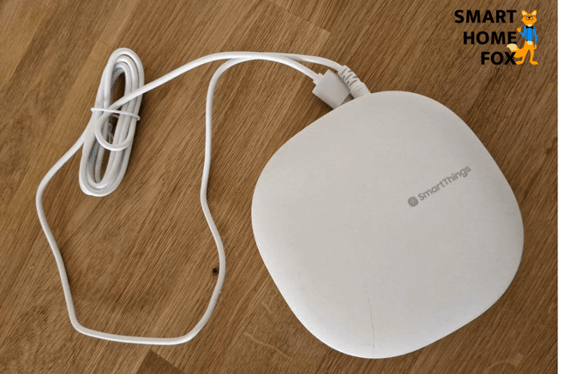 Man sieht ein Samsung SmartThings Hub auf einem Tisch liegen.